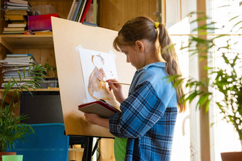 十岁的女孩吸引了油漆画架持有平板电脑电脑手