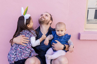快乐父亲拥抱可爱的女儿前面粉红色的墙
