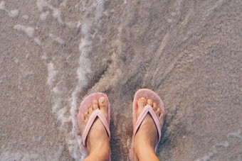 女人脚<strong>穿拖鞋</strong>站沙子热带海滩海水飞溅