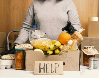 女人灰色的毛衣黑色的手套持有纸板盒子食品杂货概念援助<strong>志愿服务</strong>