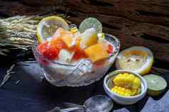 热带新鲜的水果沙拉牛奶燕麦片玻璃碗服务玉米黑暗背景