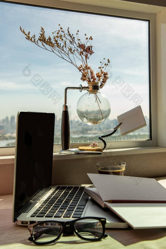 工作空间移动PC笔记本铅笔太阳镜咖啡杯干花花瓶窗口城市的观点