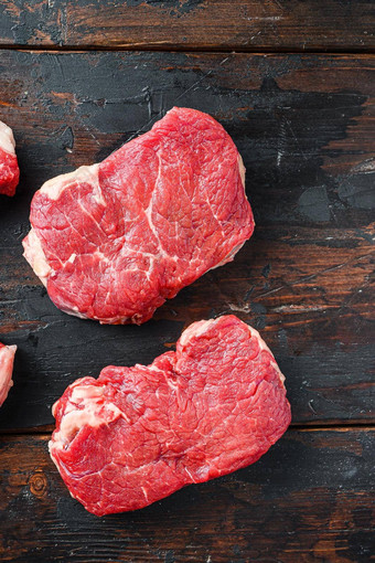 各种有机生牛肉steakes臀部减少乡村黑暗木背景前视图