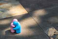 蓝色的粉红色的陶瓷夫妇娃娃拥抱石头背景