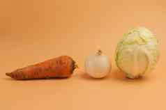 有机胡萝卜洋葱卷心菜米色背景未剥皮的甜蜜的胡萝卜洋葱卷心菜汤极简主义风格蔬菜花园维生素素食者食物健康的吃概念