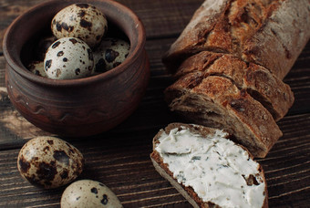 黑暗荞麦面包传播小屋奶酪草本植物减少木表格鹌鹑鸡蛋粘土板乡村风格零食早餐概念