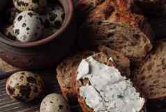 黑暗荞麦面包传播小屋奶酪草本植物减少木表格鹌鹑鸡蛋粘土板乡村风格零食早餐概念