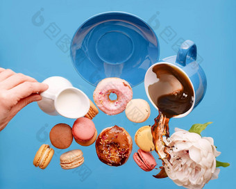 蓝色的杯咖啡甜甜圈蛋白杏仁饼牡丹手持有牛奶奶油壶飞行蓝色的背景
