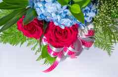 大红色的玫瑰小蓝色的脆弱的花插入叶子美丽的花花束