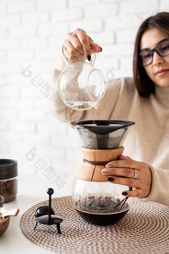 年轻的女人酝酿咖啡chemex<strong>倒热水</strong>过滤器