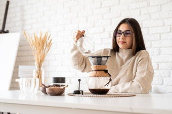 年轻的女人酝酿咖啡chemex倒热水过滤器