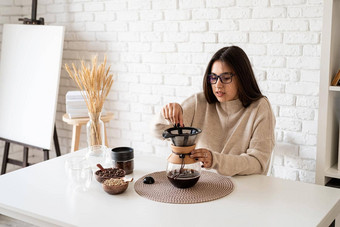 年轻的女人酝酿咖啡chemex<strong>倒热水</strong>过滤器