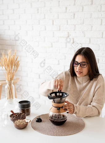 年轻的女人酝酿咖啡chemex<strong>倒热水</strong>过滤器