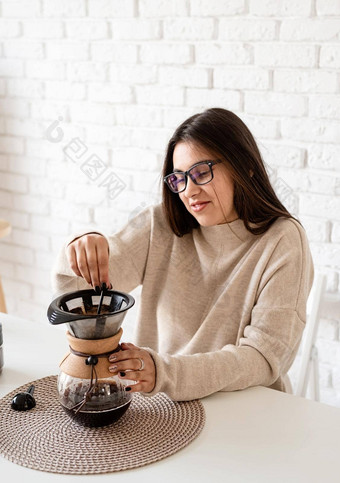 年轻的女人酝酿咖啡chemex倒热水过滤器