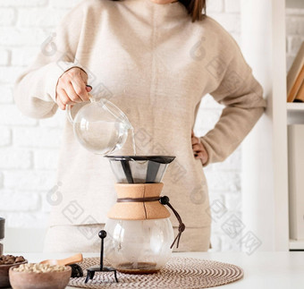 年轻的女人酝酿咖啡chemex<strong>倒热水</strong>过滤器