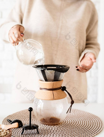 年轻的女人酝酿咖啡chemex<strong>倒热水</strong>过滤器