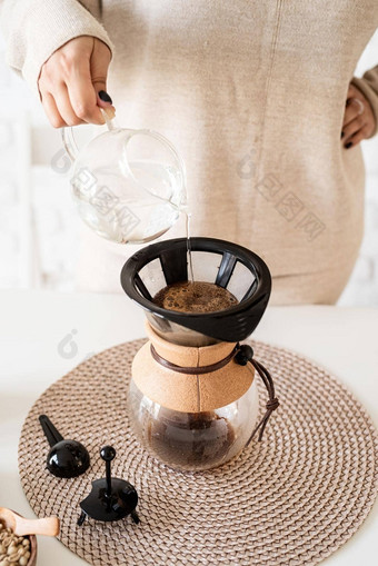 年轻的女人酝酿咖啡chemex<strong>倒热水</strong>过滤器