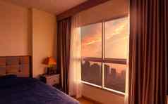 卧室早....早....阳光玻璃窗口打开窗帘奢侈品床上现代公寓城市卧室室内蓝色的毯子覆盖床上视图玻璃窗口