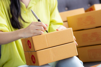 特写镜头手年轻的亚洲女人写作地址包裹盒子首页交付订单客户航运物流商人在线卖方业务老板锻造在线购物