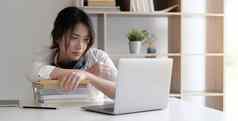 前面视图年轻的高加索人女人研究前面移动PC电脑首页女孩阅读书准备考试测试在线咨询