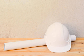 白色安全头盔塑料纸卷计划蓝图建设工程木地板上表格背景复制空间添加文本
