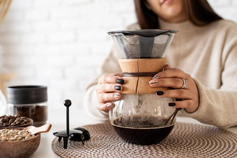年轻的女人酝酿咖啡咖啡能倒热水过滤器