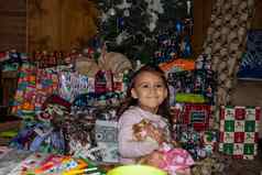 快乐女孩持有娃娃包围礼物圣诞节树