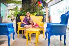 快乐妈妈。女儿坐着黄色的扶手椅小巷