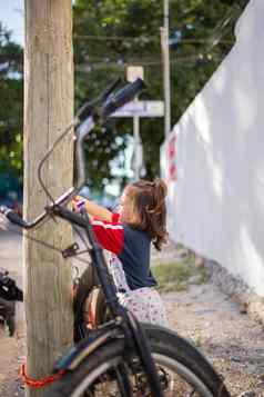 可爱的女孩玩自行车木路灯柱