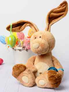 玩具兔子坐着白色背景装饰色彩斑斓的复活节鸡蛋