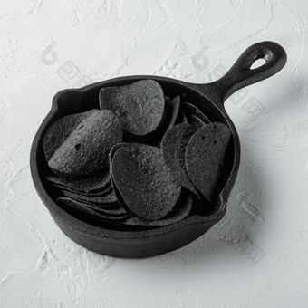 黑色的脆皮土豆<strong>芯片</strong>投铁煎锅白色石头表面广场格式