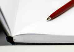 红色的圆珠笔笔空白白色页面开放笔记本