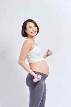 亚洲怀孕了女人锻炼站提升哑铃运动型怀孕母亲概念