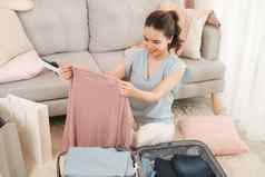 年轻的亚洲女人包装衣服旅行袋行李人概念