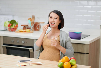 怀孕了女人持有维生素的药丸玻璃水房子厨房