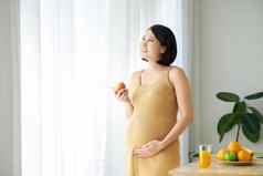 怀孕了女人站表格板新鲜的水果在室内