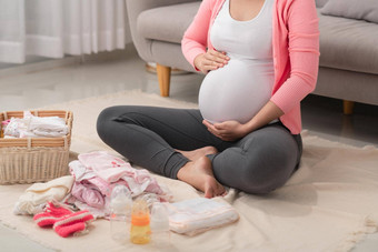 美丽的怀孕了亚洲女人包装准备婴儿衣服篮子准出生婴儿