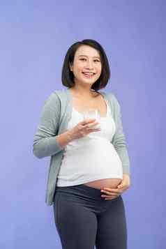 年轻的怀孕了女人玻璃牛奶紫色的背景