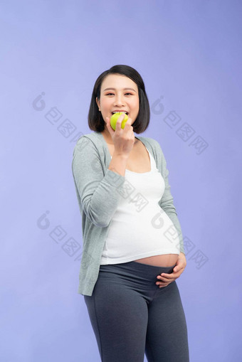 美丽的怀孕了女人持有绿色苹果孤立的淡紫色