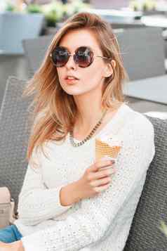 时尚美丽的女孩轮太阳镜冰奶油坐着夏天咖啡馆