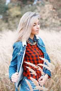时尚时尚的女孩牛仔布衣服红色的网纹衬衫秋天场草