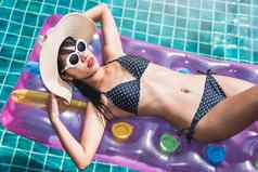 年轻的女人比基尼游泳池床垫充气浮动