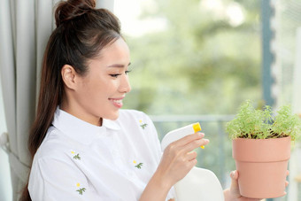 年轻的女人盆栽植物花园阳台花卉栽培爱好