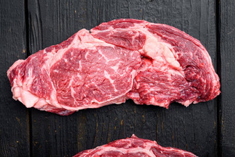 生牛脊肉牛排大理石的肉盐迷迭香大蒜黑色的木表格背景前视图平躺