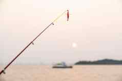 人工小鱼钓鱼杆海背景钓鱼日落