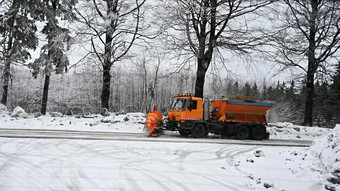 前面视图扫雪机服务卡车铺砂机车传播盐路维护道路冬天山