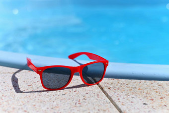 夏天背景概念夏天假期红色的太阳镜池背景蓝色的水