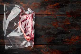 干岁的牛肉大理石的肉生新鲜的俱乐部牛排塑料包黑暗木表格背景复制空间文本