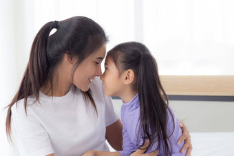 年轻的亚洲妈妈。女儿拥抱触碰鼻子脸温柔的妈妈女孩快乐的关系成键感觉情感父孩子家庭概念