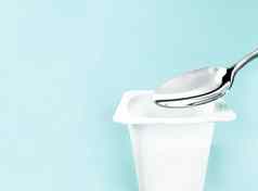 酸奶杯银勺子薄荷背景白色塑料容器酸奶奶油新鲜的乳制品产品健康的饮食营养平衡